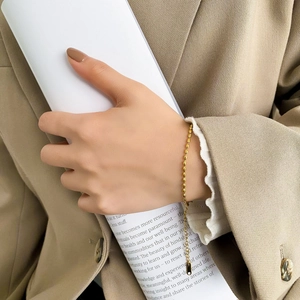 Minimalist gold oval bead bracelet for women styled with khaki suit for professional look