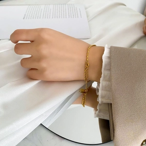 Double-layered gold titanium bracelet with minimalist rectangular tag on female wrist