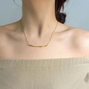 Minimalistische vergoldete Halskette mit gebogenem Stab am Modell mit schulterfreiem Top
