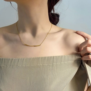 Detail der eleganten goldenen Twist-Halskette an einem Modell mit minimalistischem Stil
