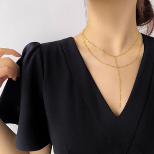 Détail d'un collier Y doré à double rangée avec pampille porté par un mannequin