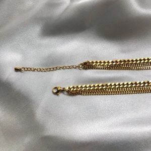 Dettaglio di collana a catena dorata a strati con chiusura a moschettone su raso