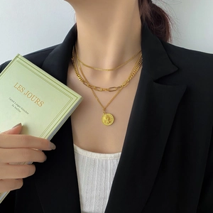 Primo piano della collana a tre strati color oro con ciondolo a moneta su una modella