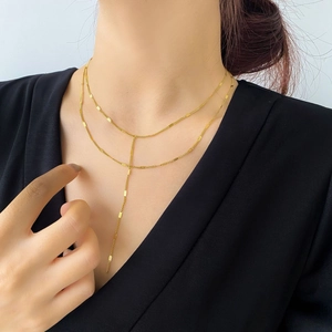 Ensemble de deux colliers dorés élégants avec pendentif pompon en Y porté par un mannequin