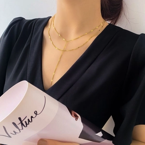 Détail d'un collier en Y doré élégant porté par un mannequin au style moderne minimaliste