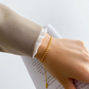 Detailed close-up of a minimalist gold beaded bracelet made of oval titanium steel beads