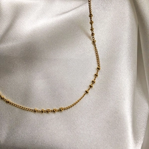 Détail macro d'un collier ras du cou doré à perles sur fond de soie blanche