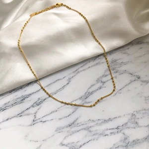 Vue détaillée d'un collier à perles plaqué or avec fermoir mousqueton et chaîne d'extension