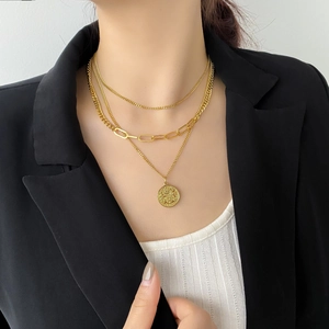 Dettaglio della collana a strati dorata con ciondolo a moneta ritratto e maglie a catena