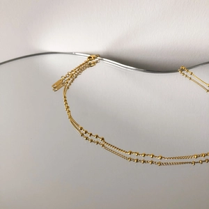 Détail du collier double couche doré avec mini perles et fermoir mousqueton réglable
