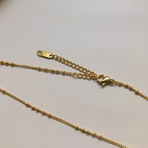 Détail du fermoir mousqueton plaqué or 18 carats et chaîne réglable avec billes