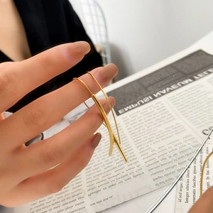 Dettaglio ravvicinato di orecchini a gancio lineari dorati lucidi con finitura moderna