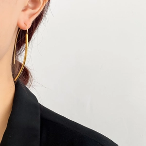 Primo piano di un orecchino pendente dorato minimalista indossato da una modella