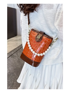 Detail of orange bucket bag with stone pattern, pearl handle and golden flower clasp