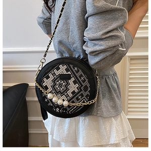 Detail of round crossbody bag with ethnic embroidery and large pearl chain accents