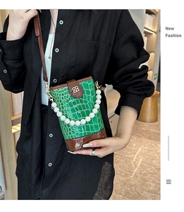 Detail of green crocodile texture bucket bag with pearl handle and metal clasp