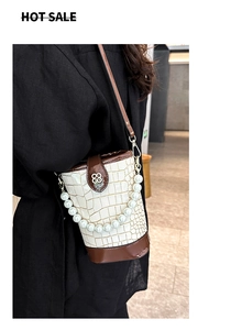 Detail of crocodile pattern bucket bag with pearl handle and contrast leather trim