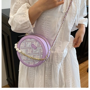 Detail of purple round crossbody bag with floral embroidery and pearl chain strap