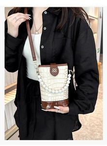 Detail of white crocodile texture bag with pearl handle and brown leather flap