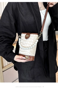 Detail of white crocodile texture bag featuring pearl handle and golden clover clasp