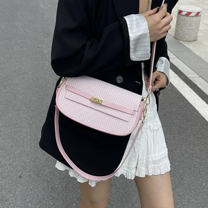 Pink and white woven crossbody bag with golden buckle and sleek leather shoulder strap