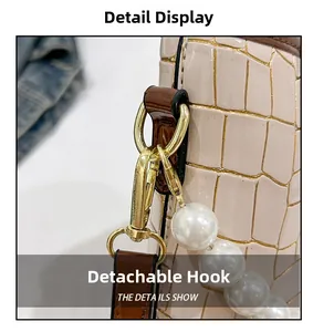 Detail of stone embossed bucket bag with gold metal clasp and pearl strap decoration