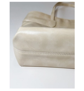 Detail showing reinforced corner structure and double stitching on the beige PU tote bag