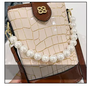 Detail of beige crocodile pattern handbag with pearl handle and golden floral clasp
