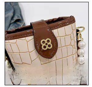 Detail of glossy stone texture leather and gold clover lock on bucket bag