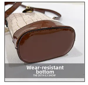 Detail view of the durable brown patent leather base on the white crocodile bucket bag