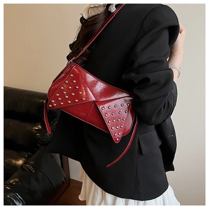 Detail of red patent leather shoulder bag with silver studs and triangular flap design