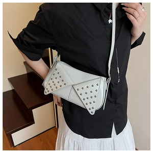 Detailed view of silver rivets on grey punk-style crossbody bag worn by a model