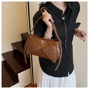 Close-up of brown punk style underarm bag with silver rivets and asymmetric leather flap