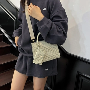 Vintage patterned crossbody bag with wide strap and mini pouch on model in minimal setting