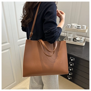 Detailed view of brown tote bag with embossed lettering and detachable shoulder strap