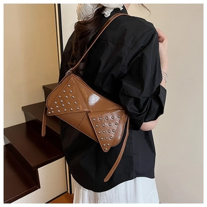 Detail of a brown vintage leather shoulder bag featuring silver rivets and a unique flap