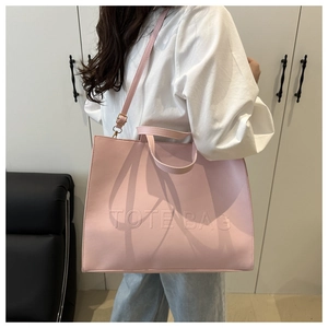 Detail showing pink faux leather tote bag with embossed letters and metal hardware