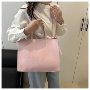 Pink tote bag detail with debossed TOTE BAG text showing handles and shoulder strap