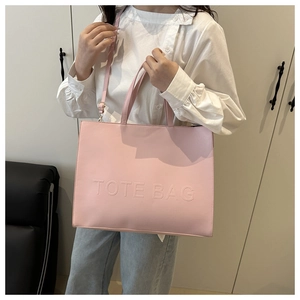 Detail of soft pink tote bag with embossed TOTE BAG text and adjustable strap