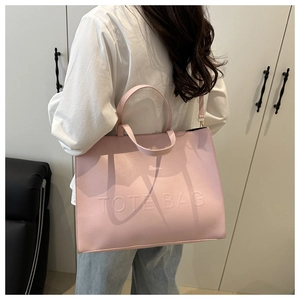 Detail of light pink tote bag with embossed lettering and long shoulder strap