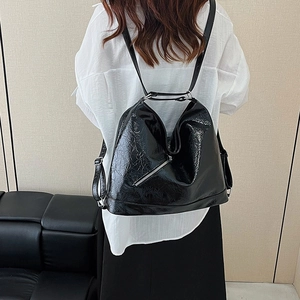 Fashionable black patent leather tote bag shown on model as a stylish shoulder bag