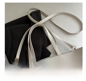 Detail view of white leather tote bag with gold metal hardware and adjustable shoulder strap