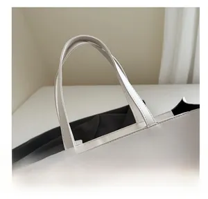 Detail of the white leather tote handle with neat stitching and minimalist matte finish