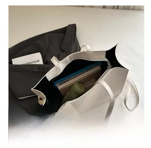 Top-down view of the large white PU leather tote bag filled with books and umbrella