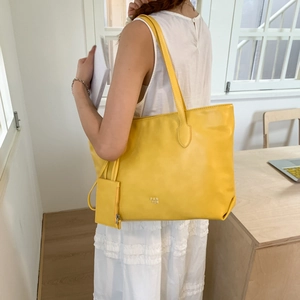 Bright yellow large leather tote bag set shown in a minimalist lifestyle indoor setting