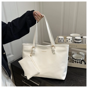 Detailed macro of white leather tote with gold logo and matching mini zipper pouch set