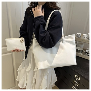 Detail of white textured leather tote bag set with adjustable strap and gold hardware