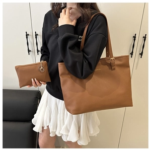 Close-up of brown tote bag set with heart keychain and adjustable gold hardware