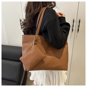 Detailed back view of a brown leather tote bag with fashion print and hanging pouch