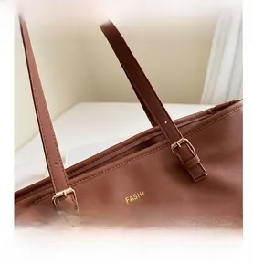 Close-up of brown Saffiano leather texture and golden metal buckle on a tote bag